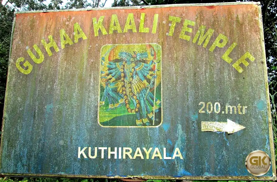 A weathered roadside signboard reading Guhaa Kaali Temple, Kuthirayala, 200 metres, with a painting of the goddess Kali